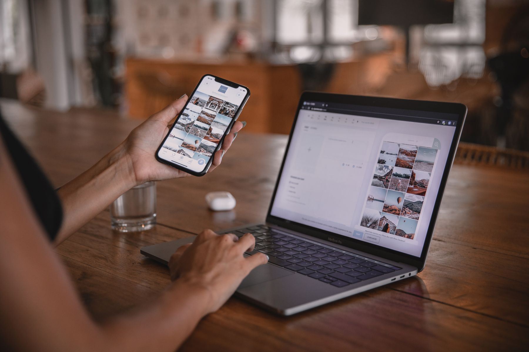 Dłonie trzymające smartfon obok otwartego laptopa